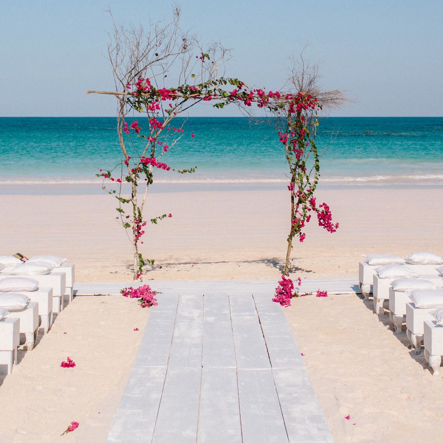 An outdoor Bahamas wedding venue at the Ocean View Club, a pink floral arch and white guest seating in front of the ocean