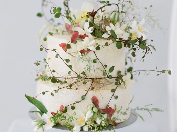 Fall white wedding cake with greenery, white flowers, and red leaves
