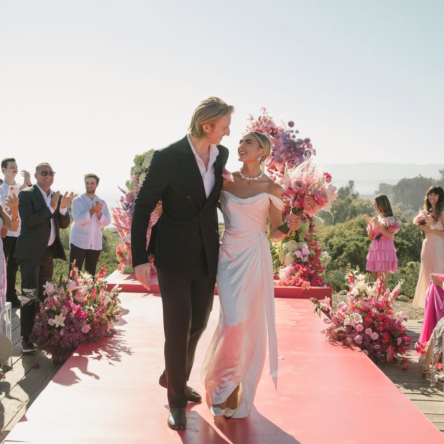 Bride and groom looking at each other and smiling while standing on their hot pink aisle