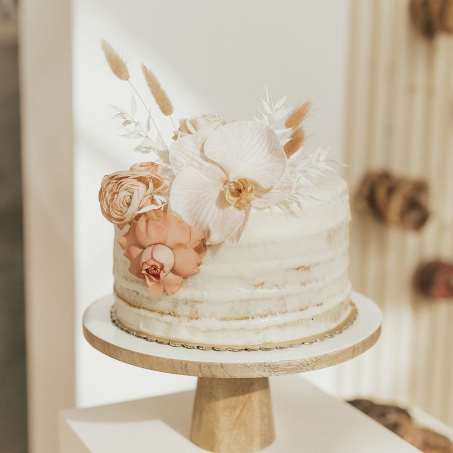A small wedding cake with white icing and white and pink fresh flowers. 