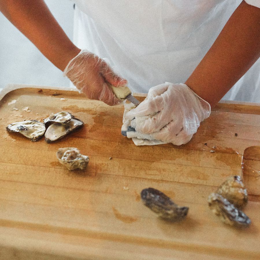 A person wearing gloves and shucking oysters at a wedding.