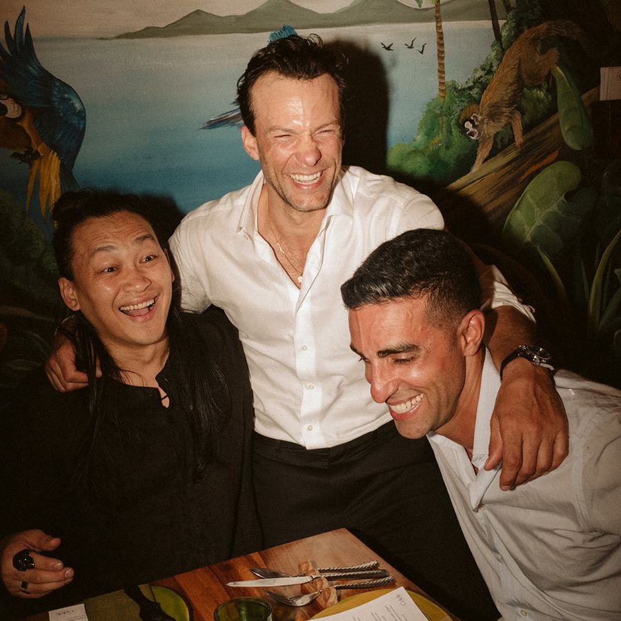 Three guys laughing together at dinner table