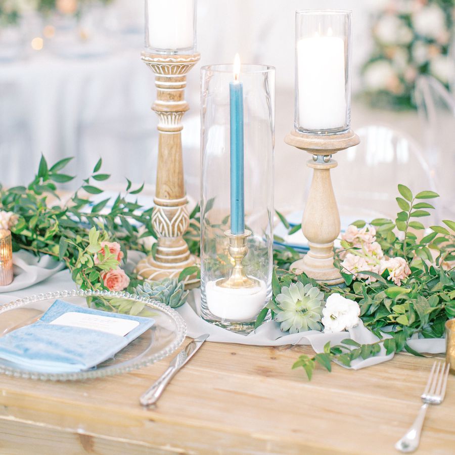 light brown reception table with greenery centerpiece with succulents and tall candles