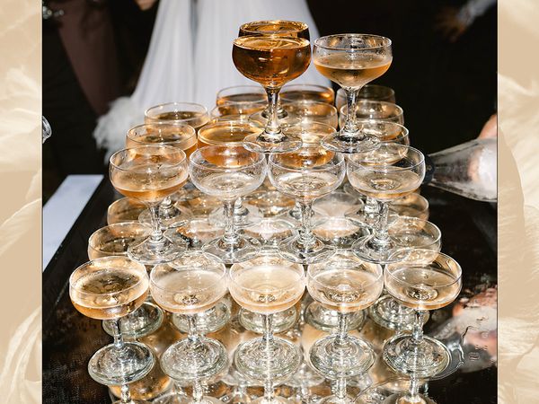 Pouring champagne over a champagne tower at a wedding.