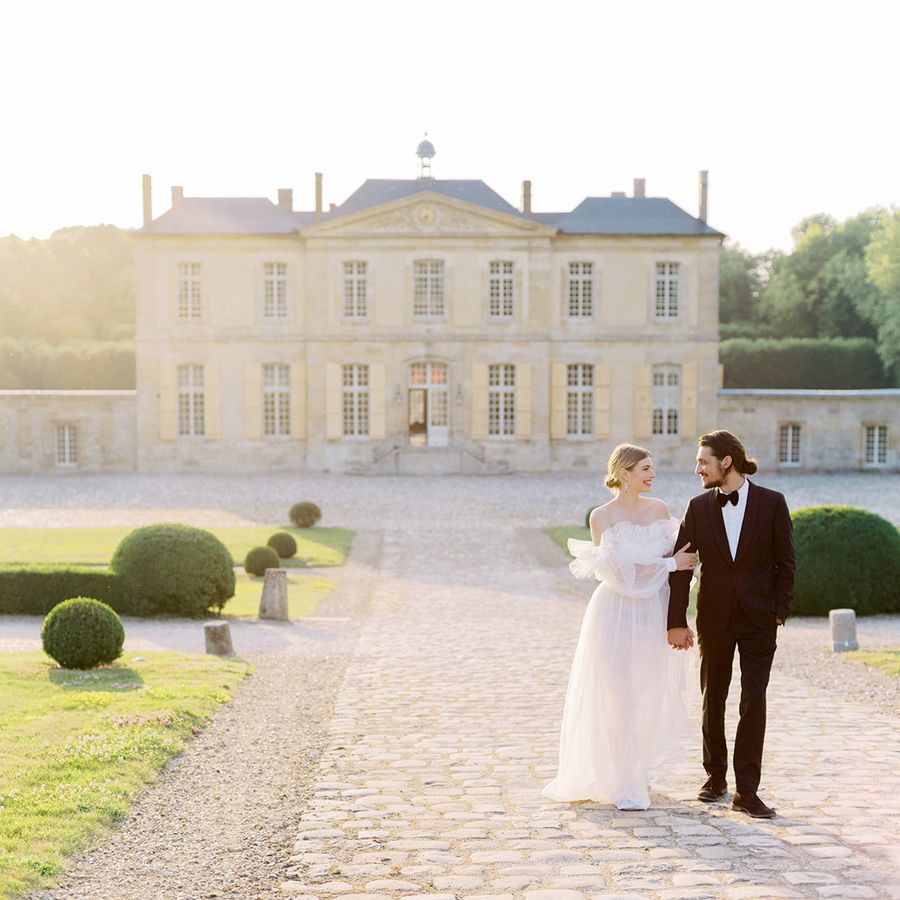 A bride and groom walk outside their wedding venue in France.