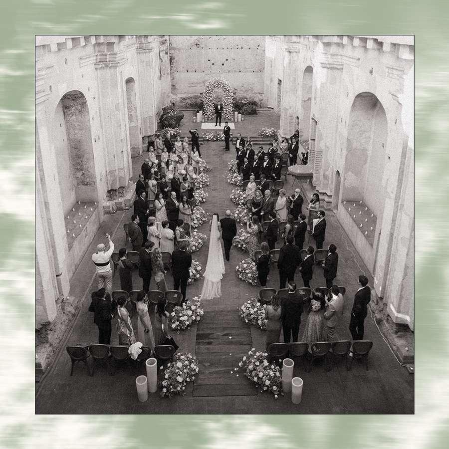 wedding ceremony processional in old castle with flower-lined aisle