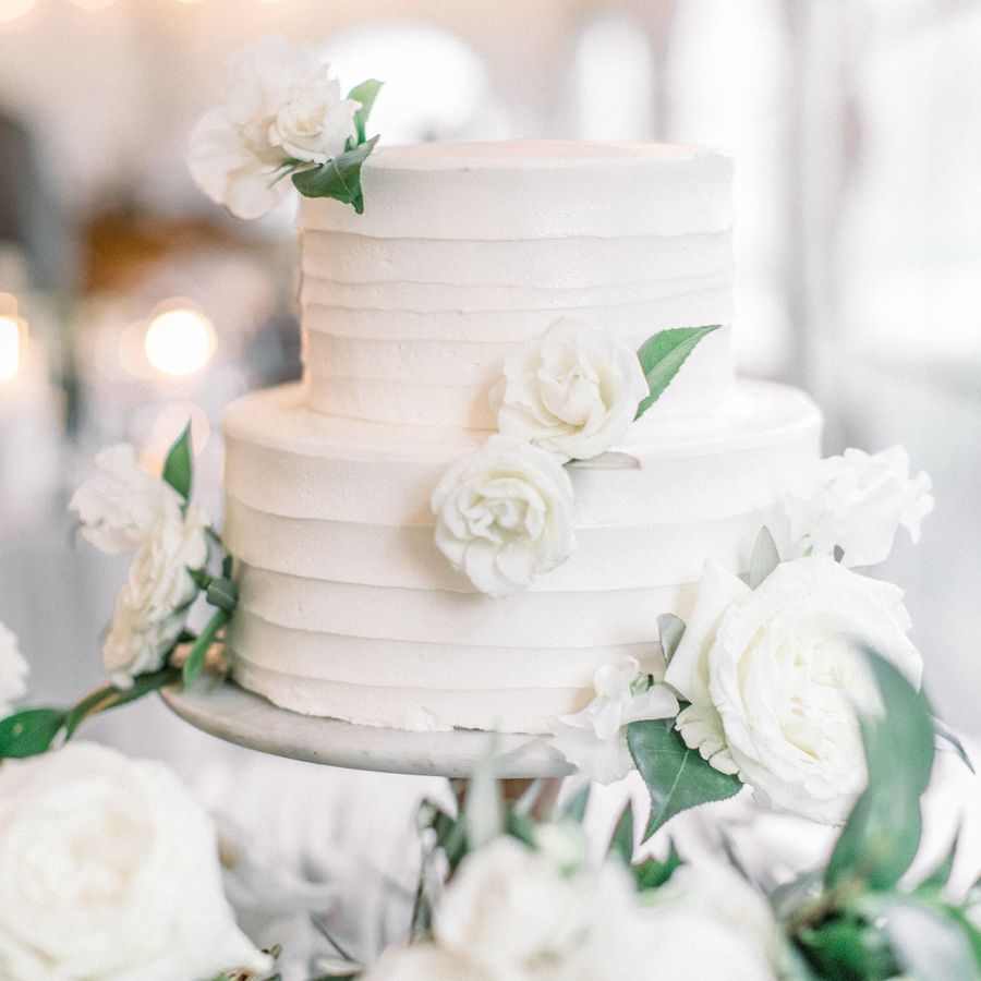 two tier white wedding cake decorated with textured buttercream and white florals
