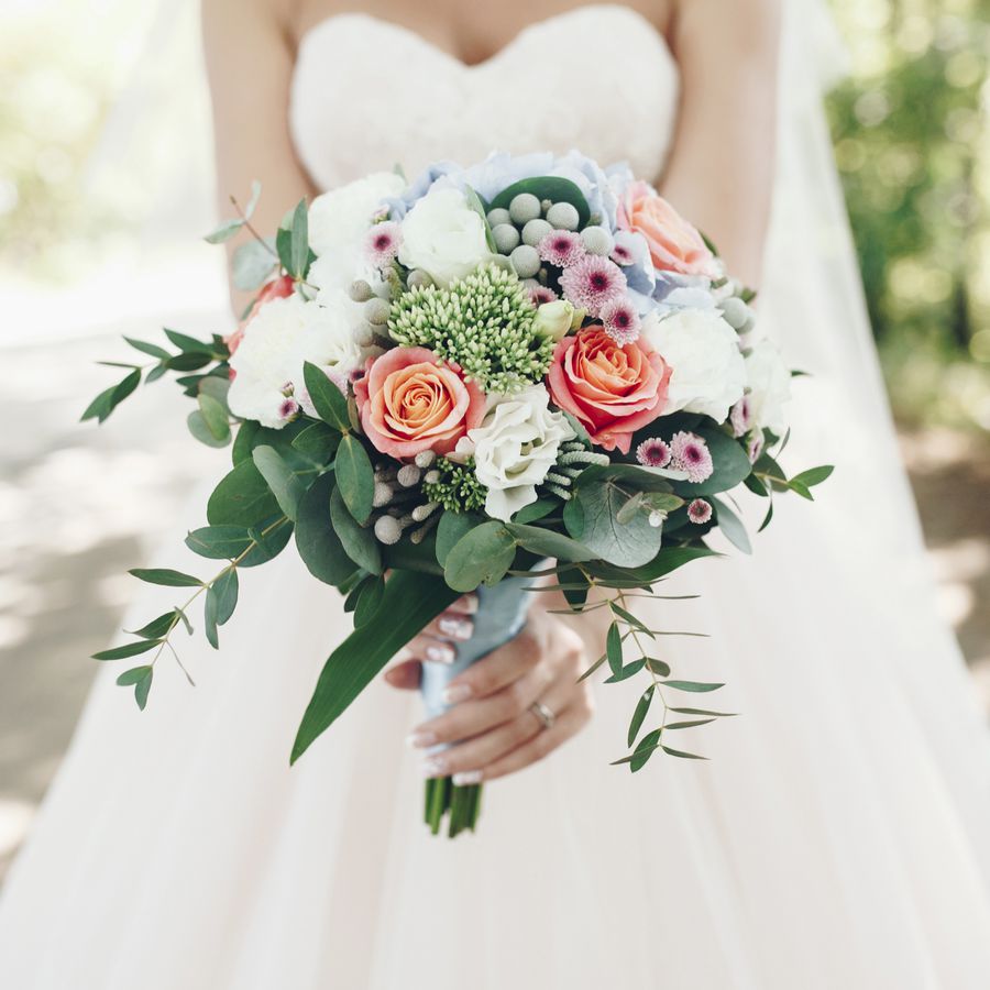 A bride wearing a strapless wedding dress, holding a colorful bouquet