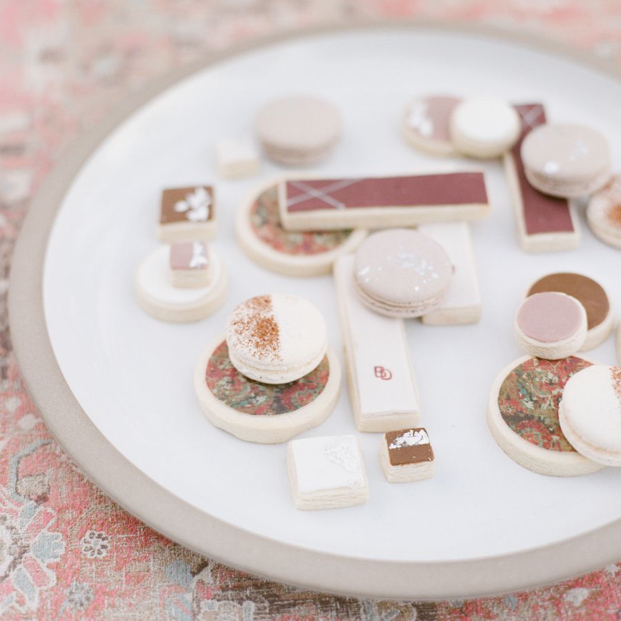 An assortment of cookies with pink icing on a white plate served at a wedding reception.