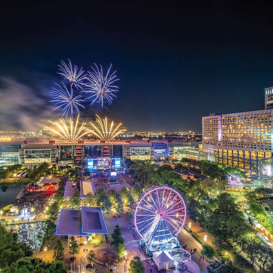 A drone shot of Discovery Green at night with fireworks in Houston