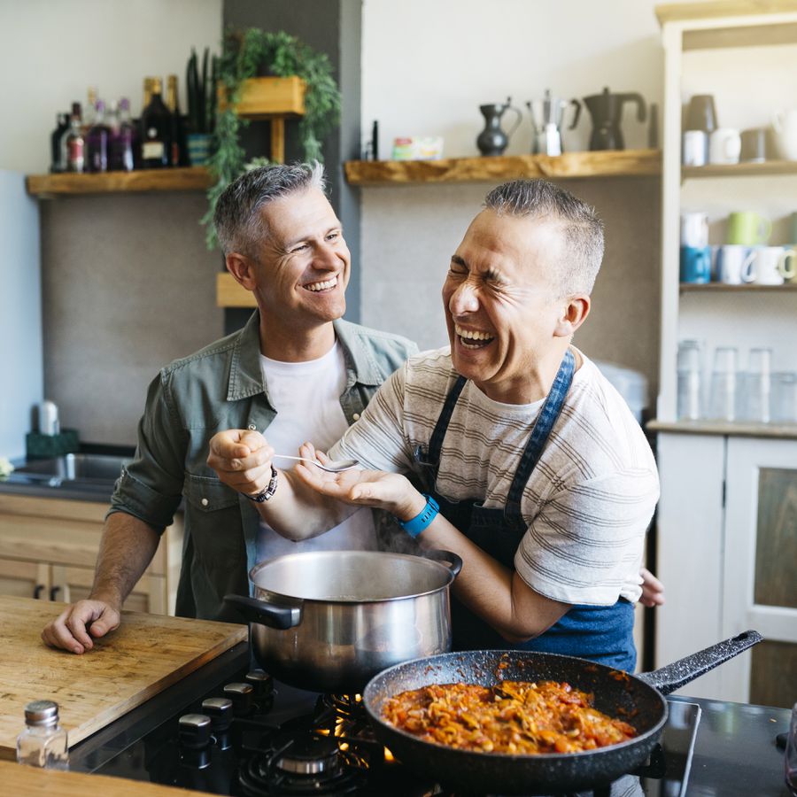A gay couple cooks pasta together in their kitchen at home.