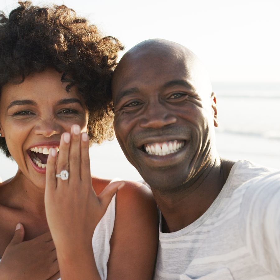 Happy engaged couple with woman showing off ring