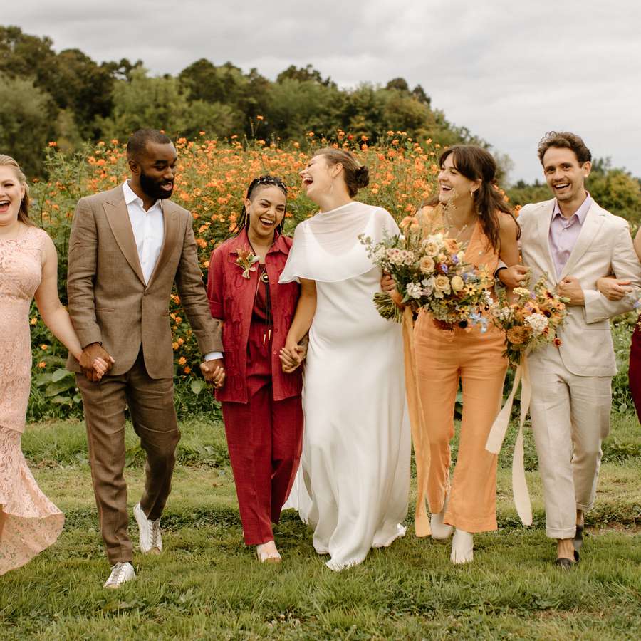 Bride and Wedding Party in Mismatched Attire Walking Through Flower Field