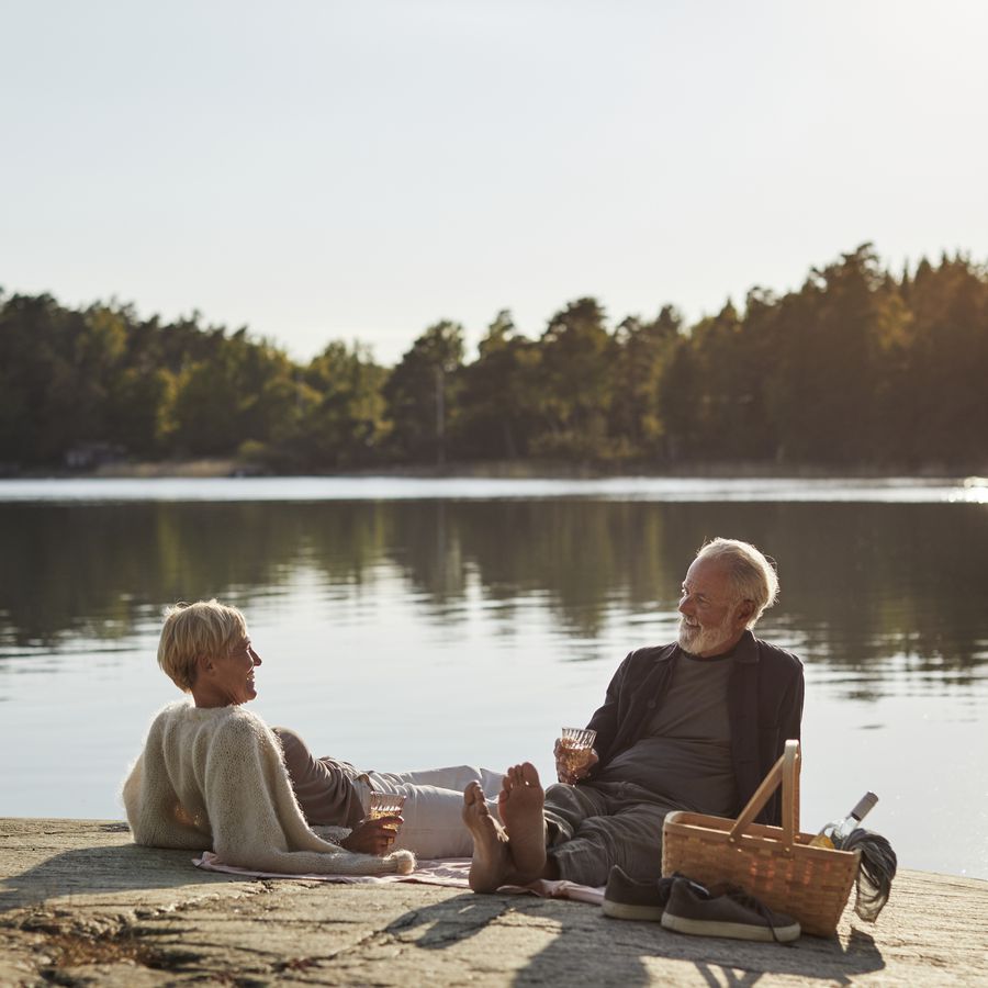 Senior couple lounging on a rock next to a lake