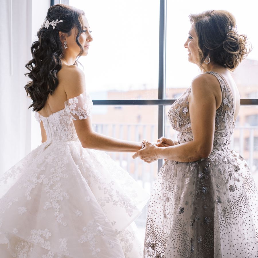 bride holding hand with her mother by a window