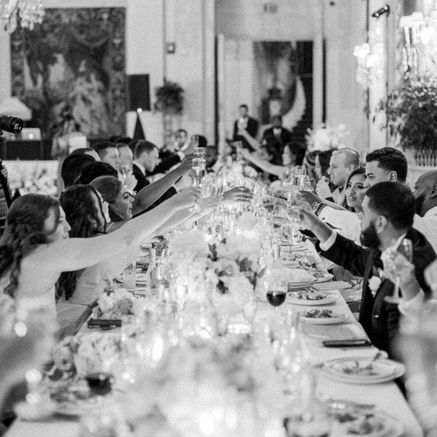 guests toasting with champagne glasses at long wedding reception table