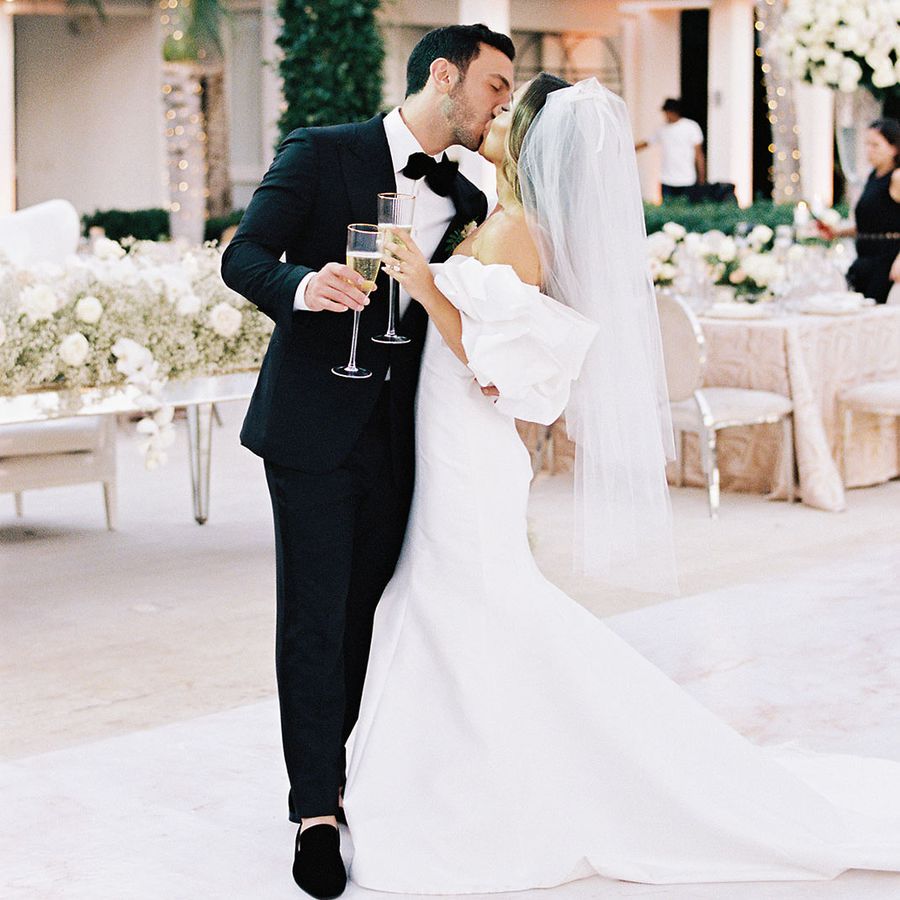 a bride and groom kissing while holding glasses of champagne