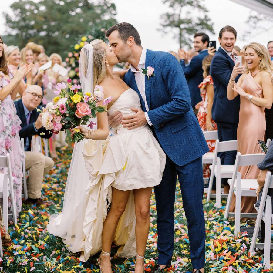 Couple kissing in the middle of their aisle covered in confetti
