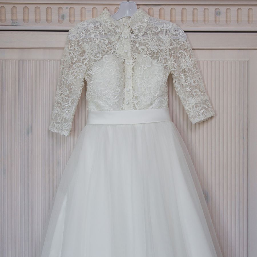 A wedding dress with a lace bodice and tulle skirt hanging on a hanger