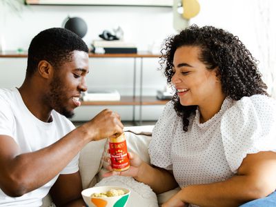 man and woman eating on couch at home