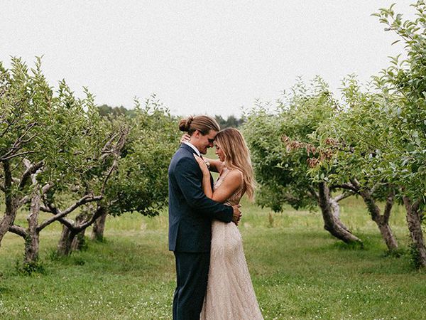 Bride and groom in an apple orchard field surrounded by apple trees at The Meadow Barn in South Dakota.