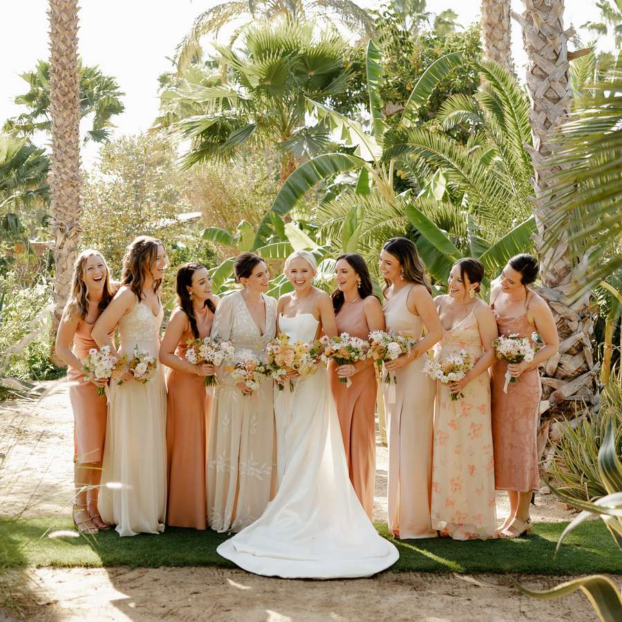 bridesmaids wearing pink dresses with palm trees in the background