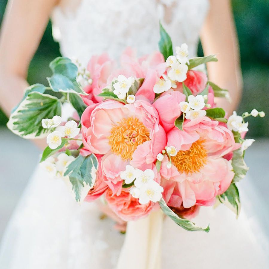 Pink peonies in a bridal bouquet with small white accent flowers and greenery.