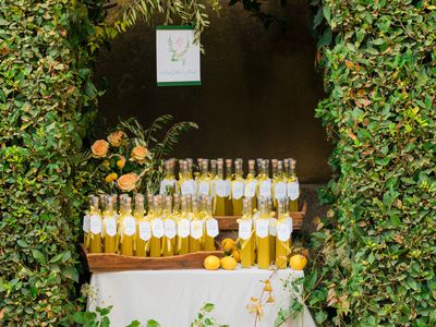 Bottles of limoncello affixed with custom labels presented on a table covered in white linens and framed by boxwood