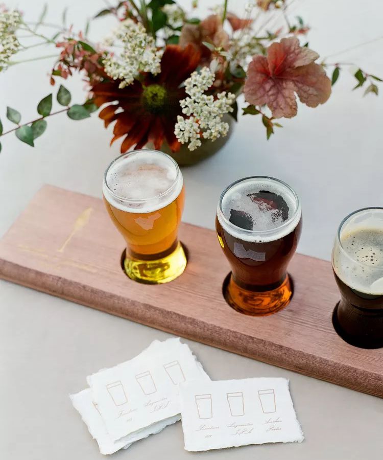 A beer flight on a white table with pink and white flowers at a brewery wedding venue.