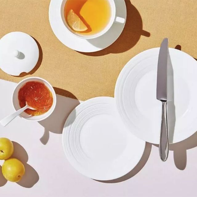 White dish set displayed on a brown table with tea and a dish of jam