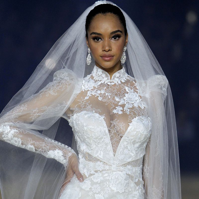 A model wearing a lace wedding gown with a veil by 