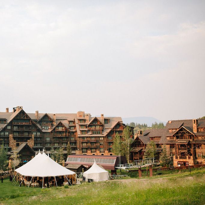 A white wedding tent outside of a Colorado ski resort near the ski lift and ski mountain in the summertime.