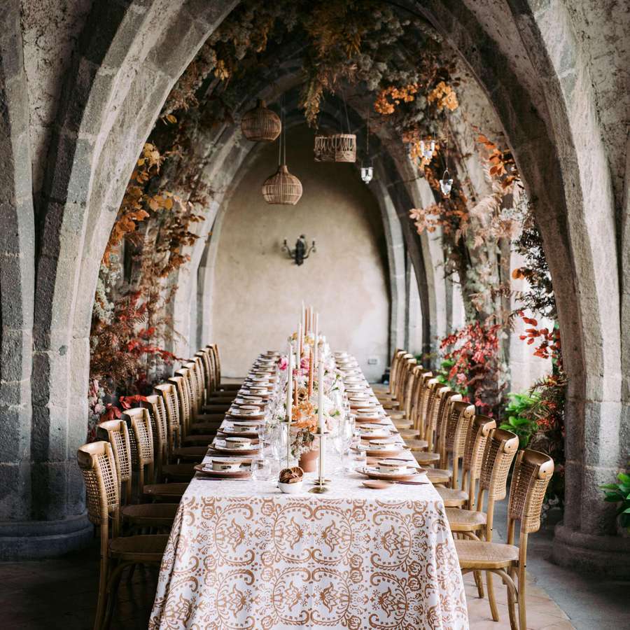 Wedding tablescape with brown linens, florals in arches, and brown chairs