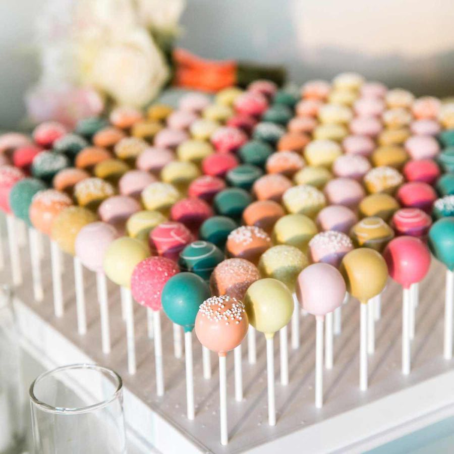 Wedding cake pops in orange, green, yellow, pink shades on stand