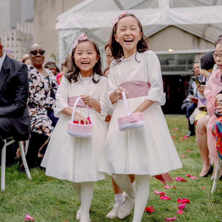 Two flower girls walking down aisle in pink and white dresses