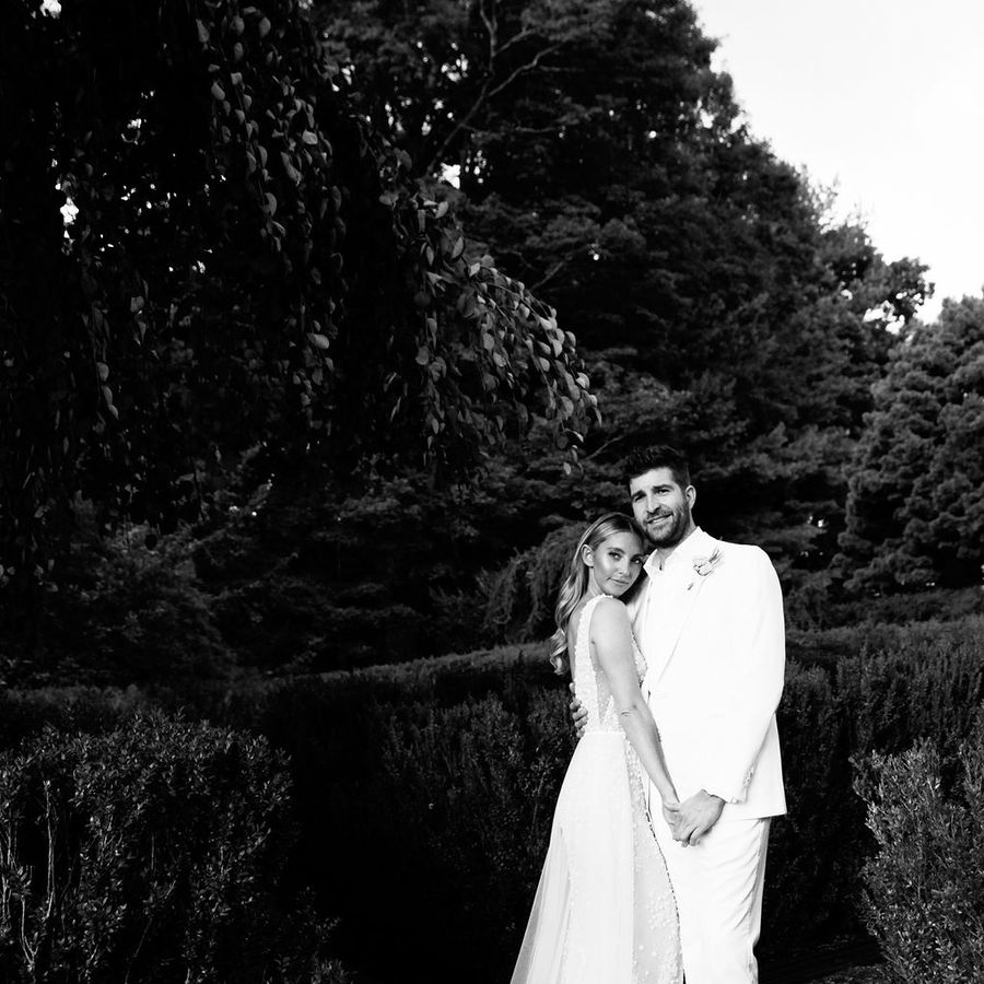 black and white portrait of bride in Lee Petra Grebenau and groom in white tux standing in garden