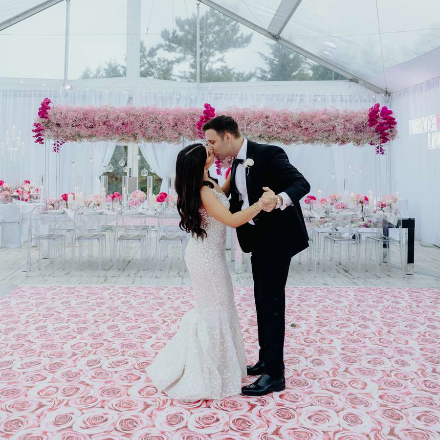 Bride and groom kissing on their pink rose-inspired dance floor