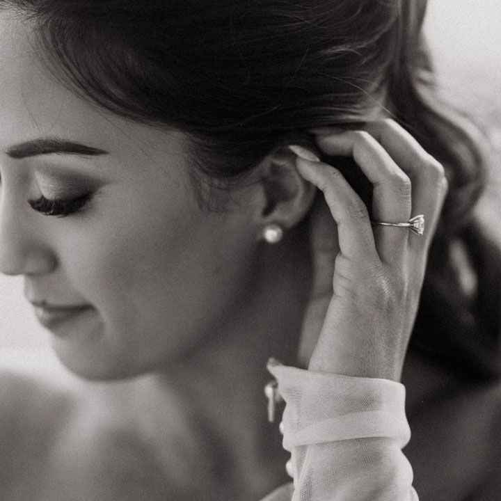 black and white photo of bride with diamond ring and pearl earrings 