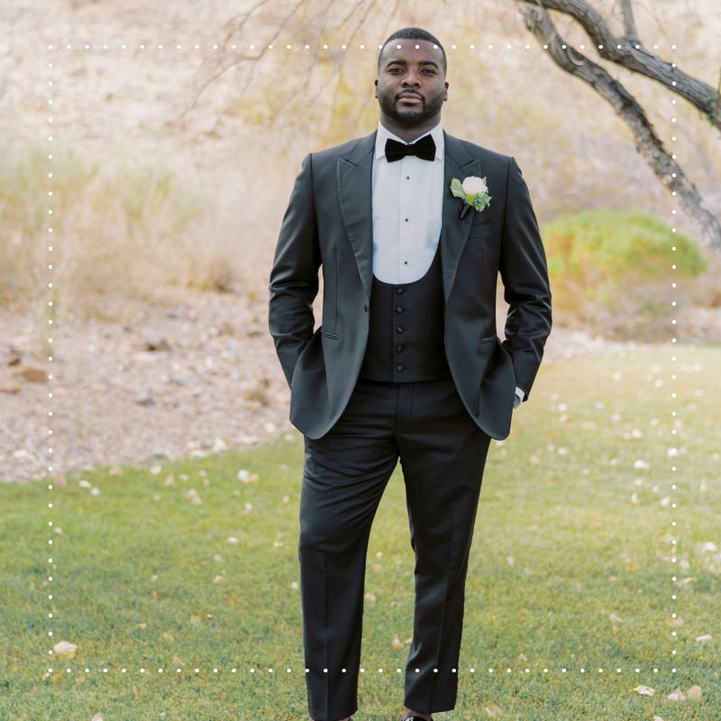 groom wearing a black tuxedo with a bow tie and boutonniere 