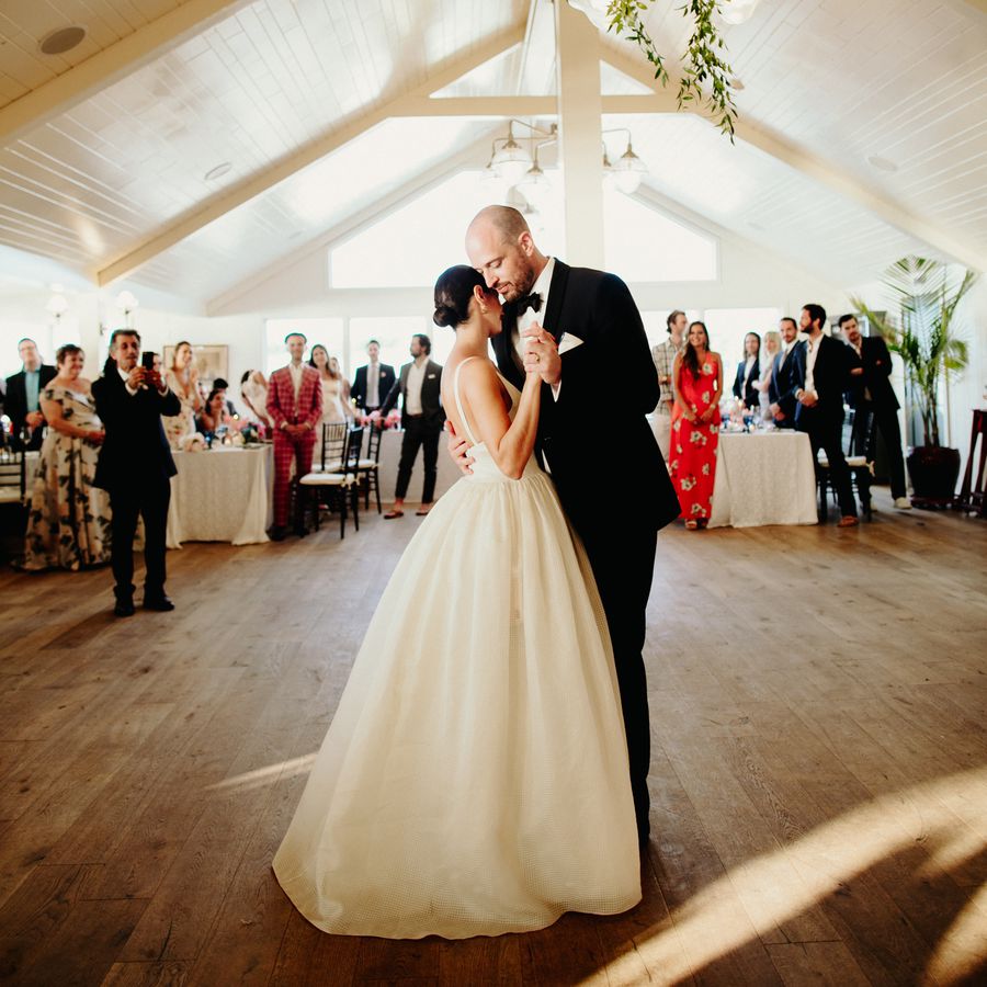 Bride and groom slow dancing in an A-frame style reception area surrounded by guests.