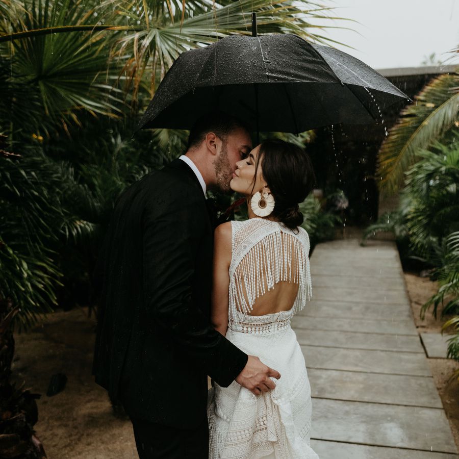 Couple kissing underneath an umbrella in the rain