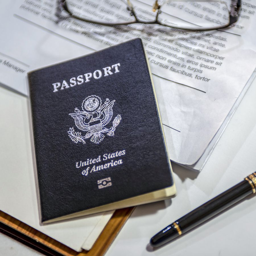 Photo of a United States passport on top of a piece of paper with glasses and a pen