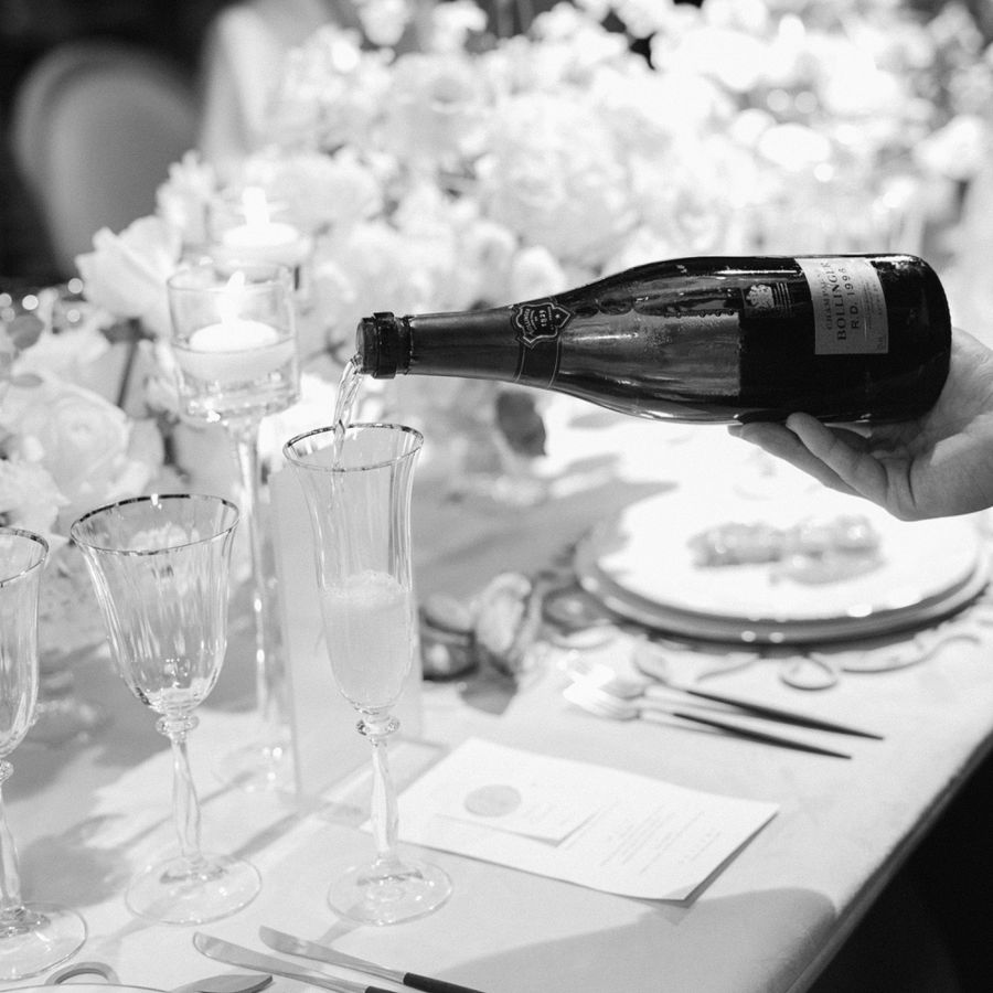 Server Pouring Chilled Champagne Into Crystal Flutes on Wedding Reception Tables