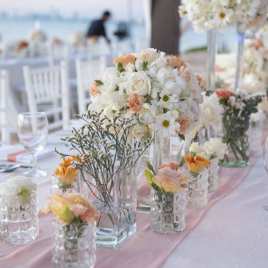 A bouquet of white and orange wedding flowers on a wedding reception table.