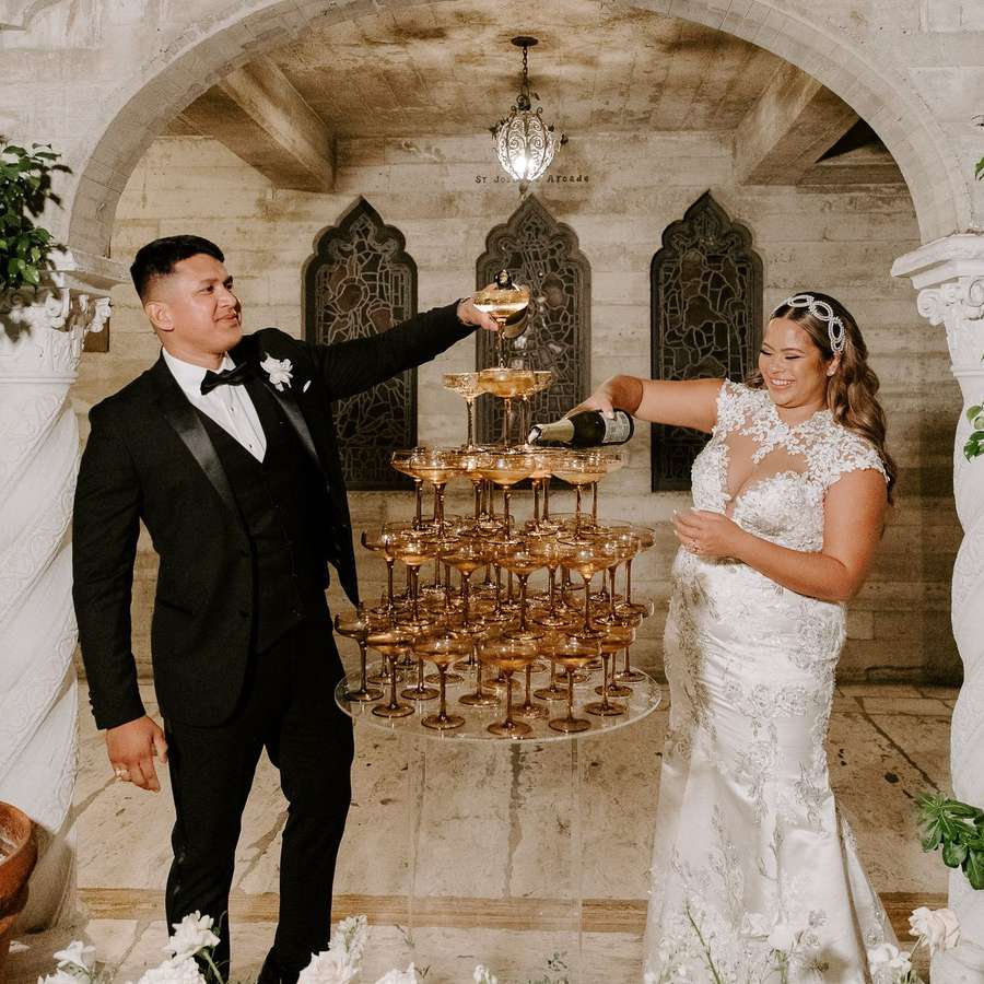couple pouring champagne on tower at wedding