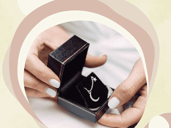 A black necklace box containing a delicate silver chain necklace with moon and star charms.